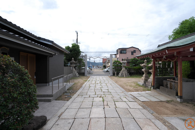 拝殿前より注連柱を望む。かつてはクルマの止まっているすぐ先が海だったようだ。海の向こうに見えるのは淡路島、淡路島との関係が深いのかもしれない。